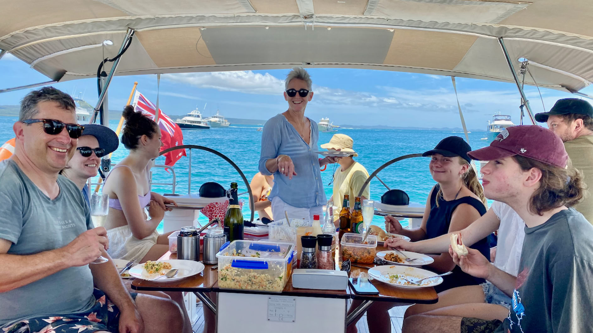 Family celebrating a birthday party gathered around the cockpit table on the yacht on a private yacht charter at Peel Island Moreton Bay.