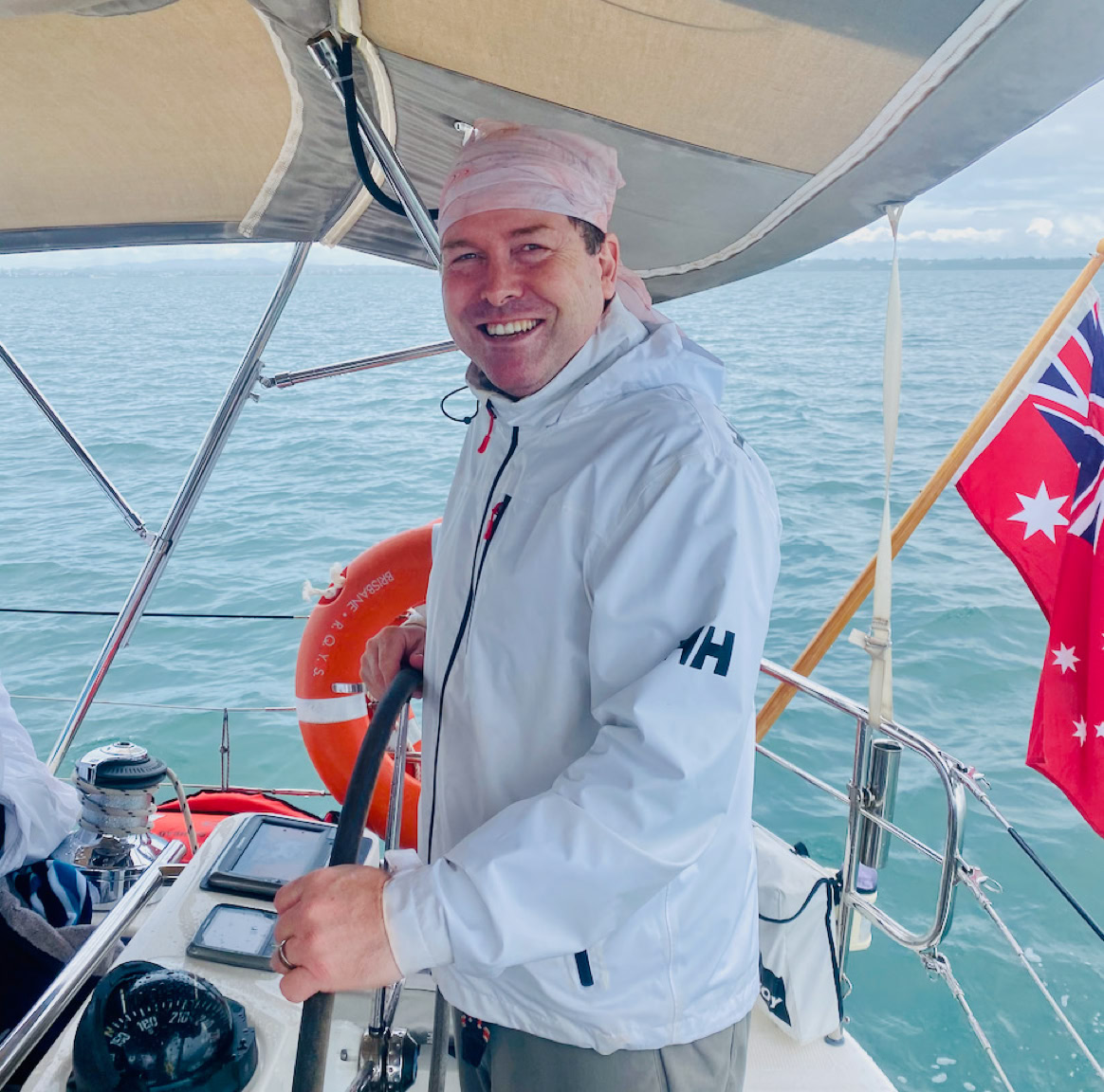 Skipper on the wheel on a private yacht charter on Curlew Escape, Moreton Bay, Brisbane.
